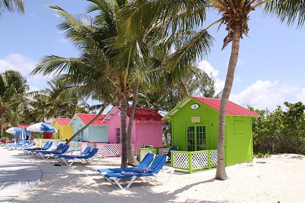Bunte Strand-Hütten: Resort in den Bahamas am Strand entdecken und in Liegestühlen entspannen. 
